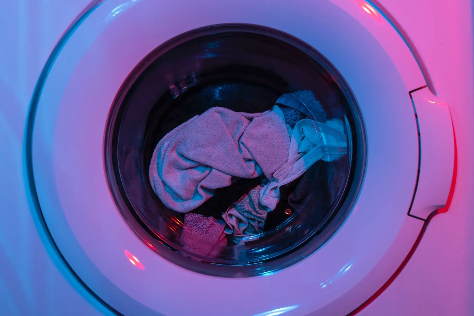 Washing machine full of clothes with pink light glow